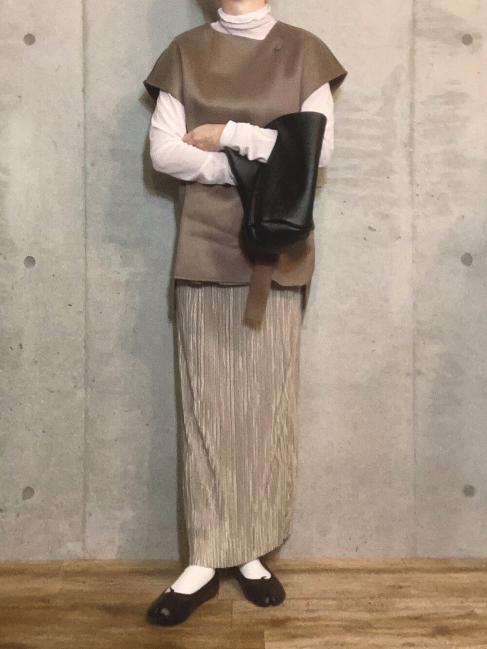 ホワイト系のTシャツ/カットソー、ベージュ系のベスト、ブラック系のトートバッグを着用したレディースの冬コーディネートの2枚目の写真