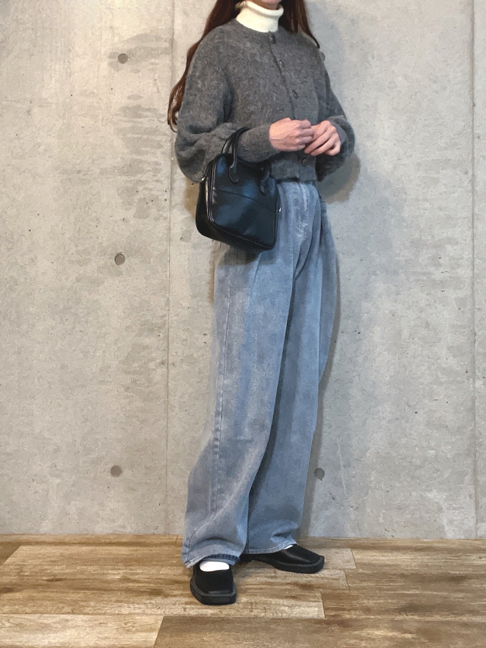 グレー系のカーディガン/ボレロ、ブラック系のショルダーバッグ、ブルー系のデニムパンツを着用したレディースの冬コーディネートの2枚目の写真