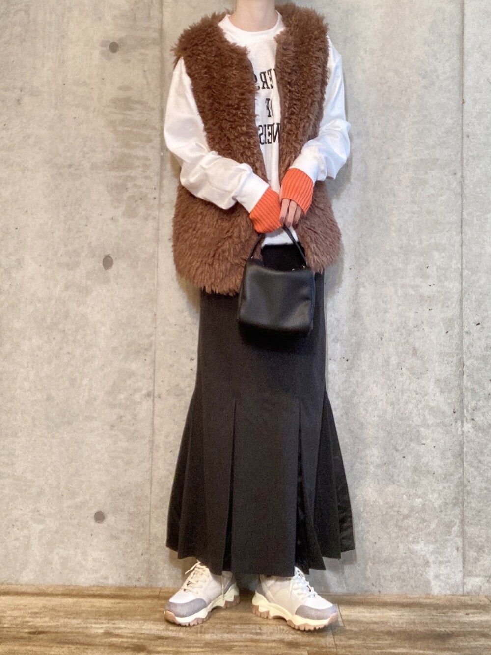 ブラウン系のベスト、グリーン系のモッズコート、ブラック系のショルダーバッグを着用したレディースの秋コーディネートの2枚目の写真