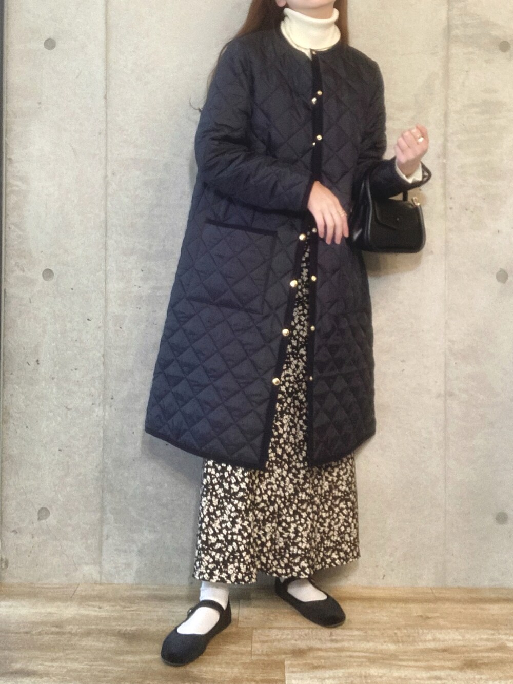 ブルー系のノーカラーコート、ホワイト系のニット/セーター、ブラック系のショルダーバッグを着用したレディースの秋コーディネートの2枚目の写真