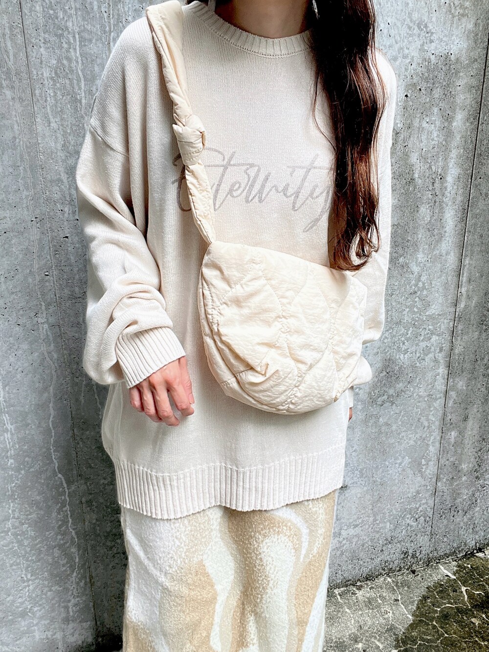 ホワイト系のニット/セーター、ホワイト系のショルダーバッグ、ホワイト系のスニーカーを着用したレディースの秋コーディネートの2枚目の写真