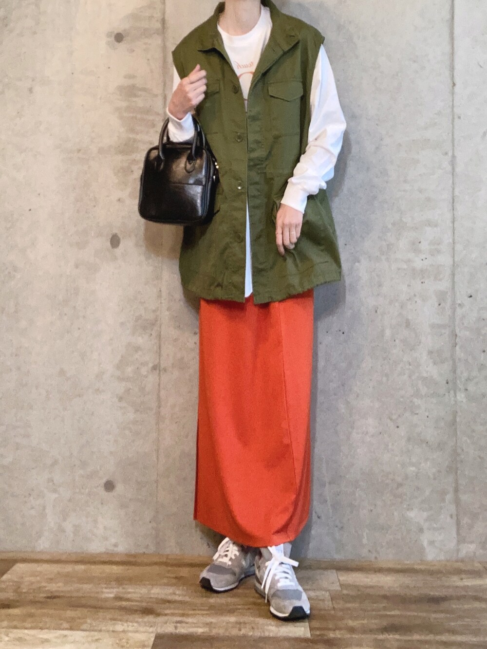 グリーン系のベスト、ホワイト系のTシャツ/カットソー、ブラック系のショルダーバッグを着用したレディースの春コーディネートの3枚目の写真