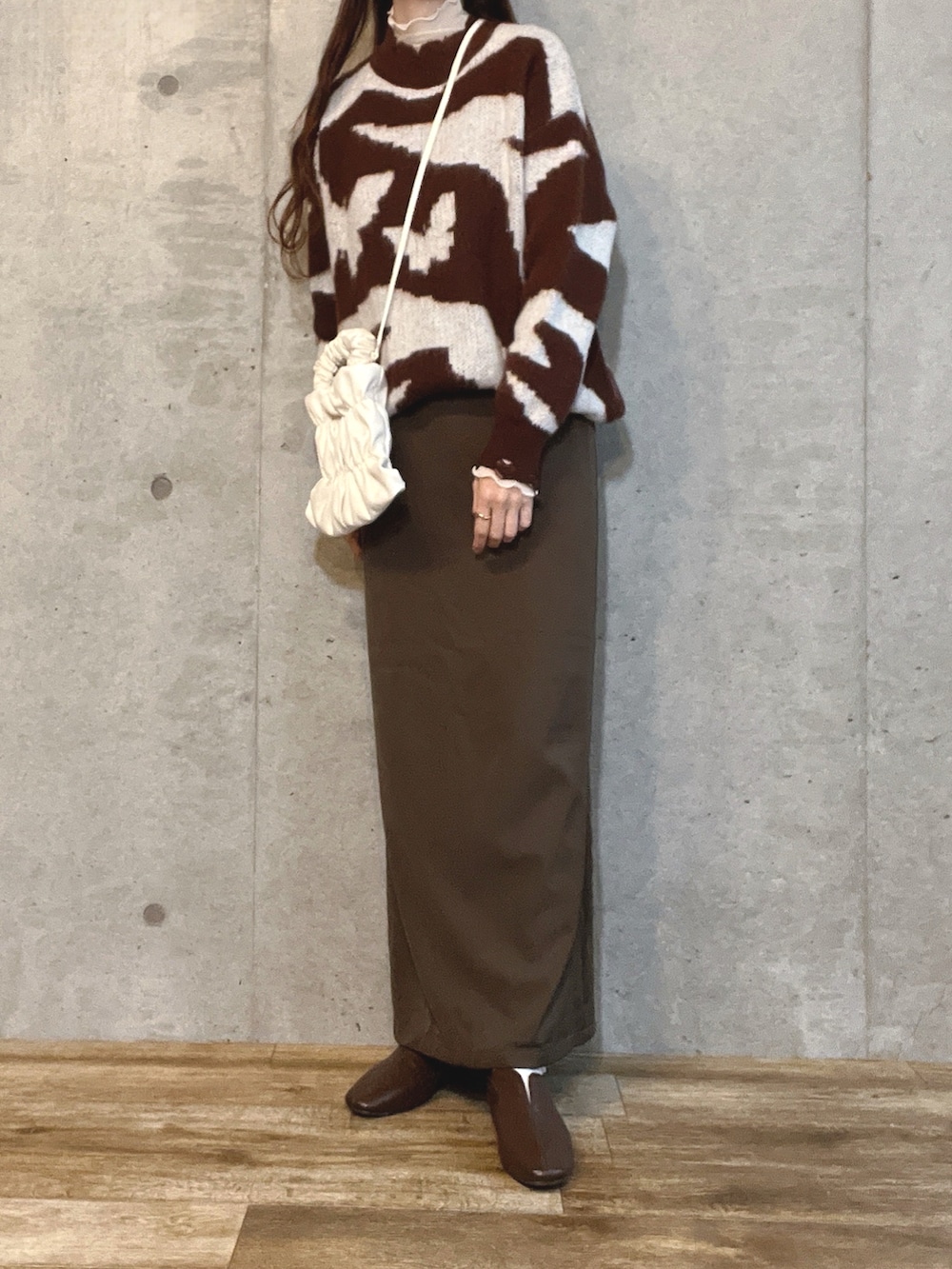 ブラウン系のニット/セーター、ホワイト系のショルダーバッグ、ブラウン系のワンピースを着用したレディースの春コーディネートの2枚目の写真