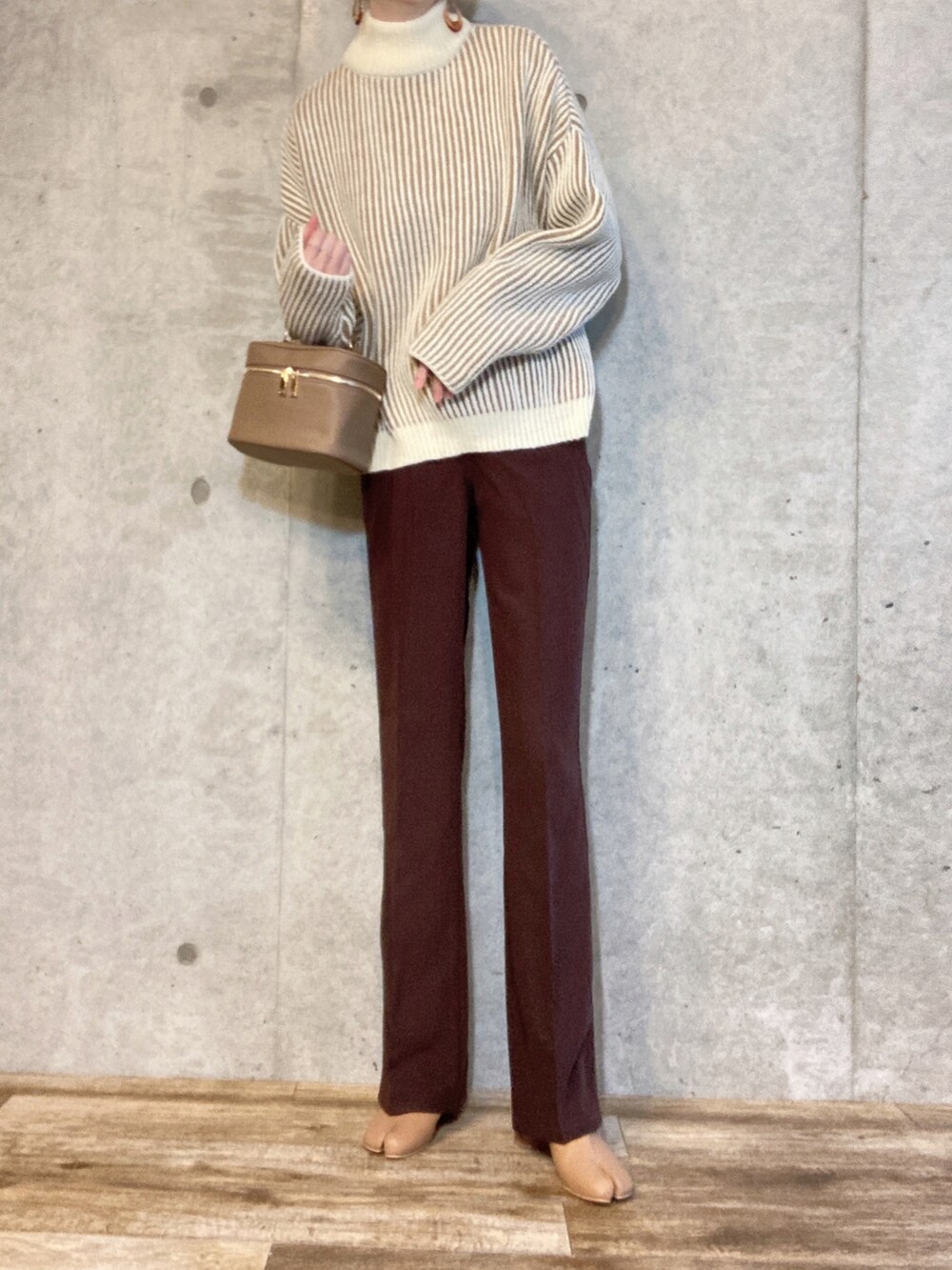 ベージュ系のニット/セーター、ベージュ系のハンドバッグ、ブラウン系のその他パンツを着用したレディースの冬コーディネートの2枚目の写真