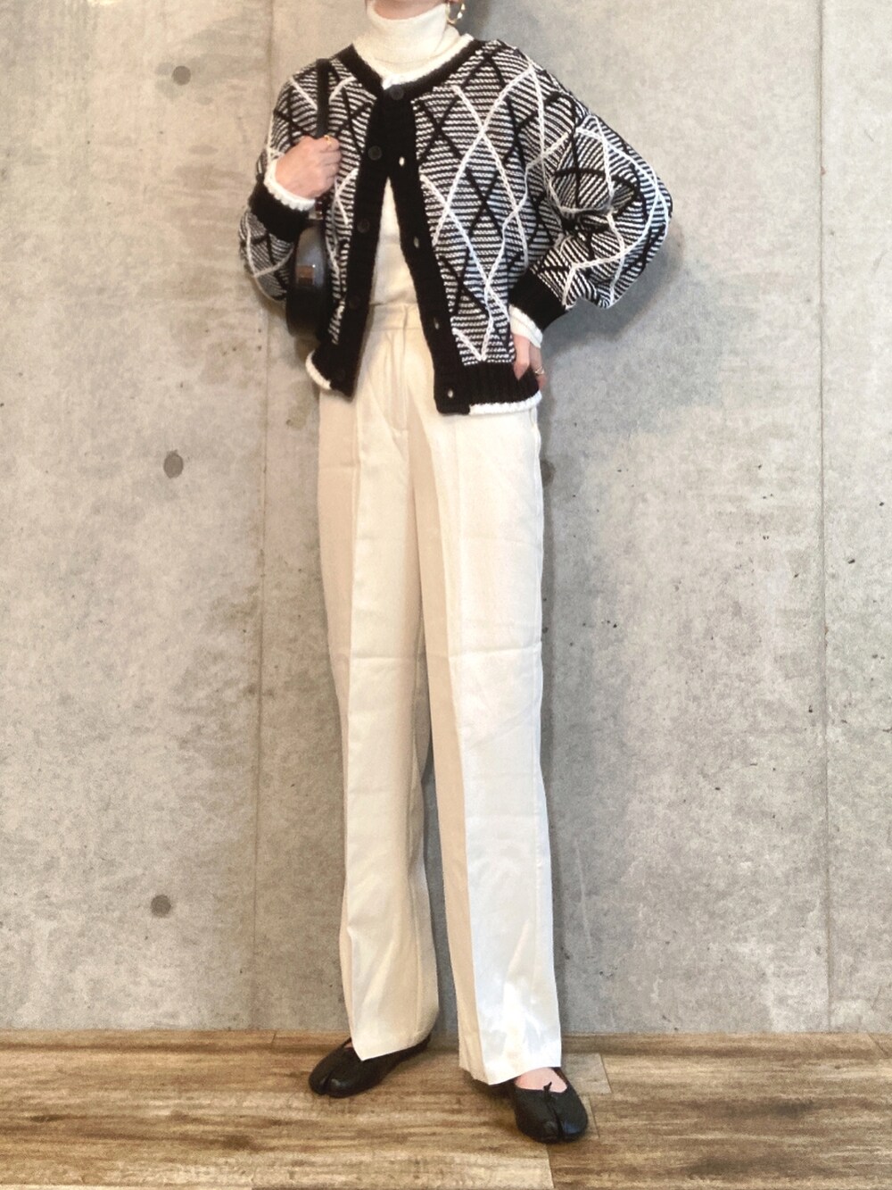 ブラック系のカーディガン/ボレロ、ホワイト系のニット/セーター、ブラック系のハンドバッグを着用したレディースの秋コーディネートの2枚目の写真