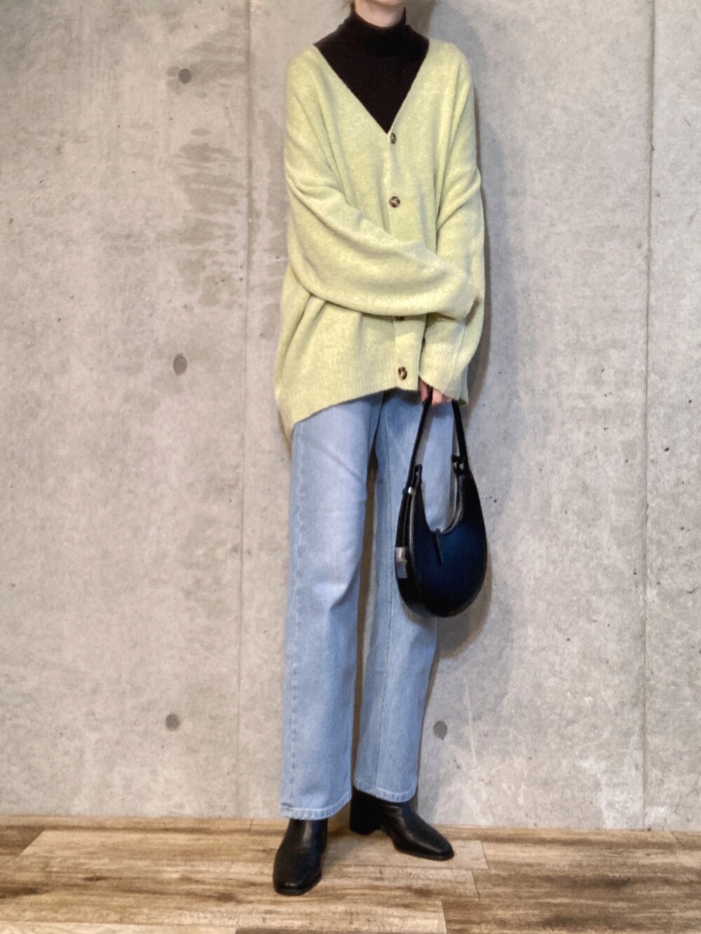 ブラック系のニット/セーター、ブラック系のハンドバッグ、ブルー系のデニムパンツを着用したレディースの冬コーディネートの2枚目の写真