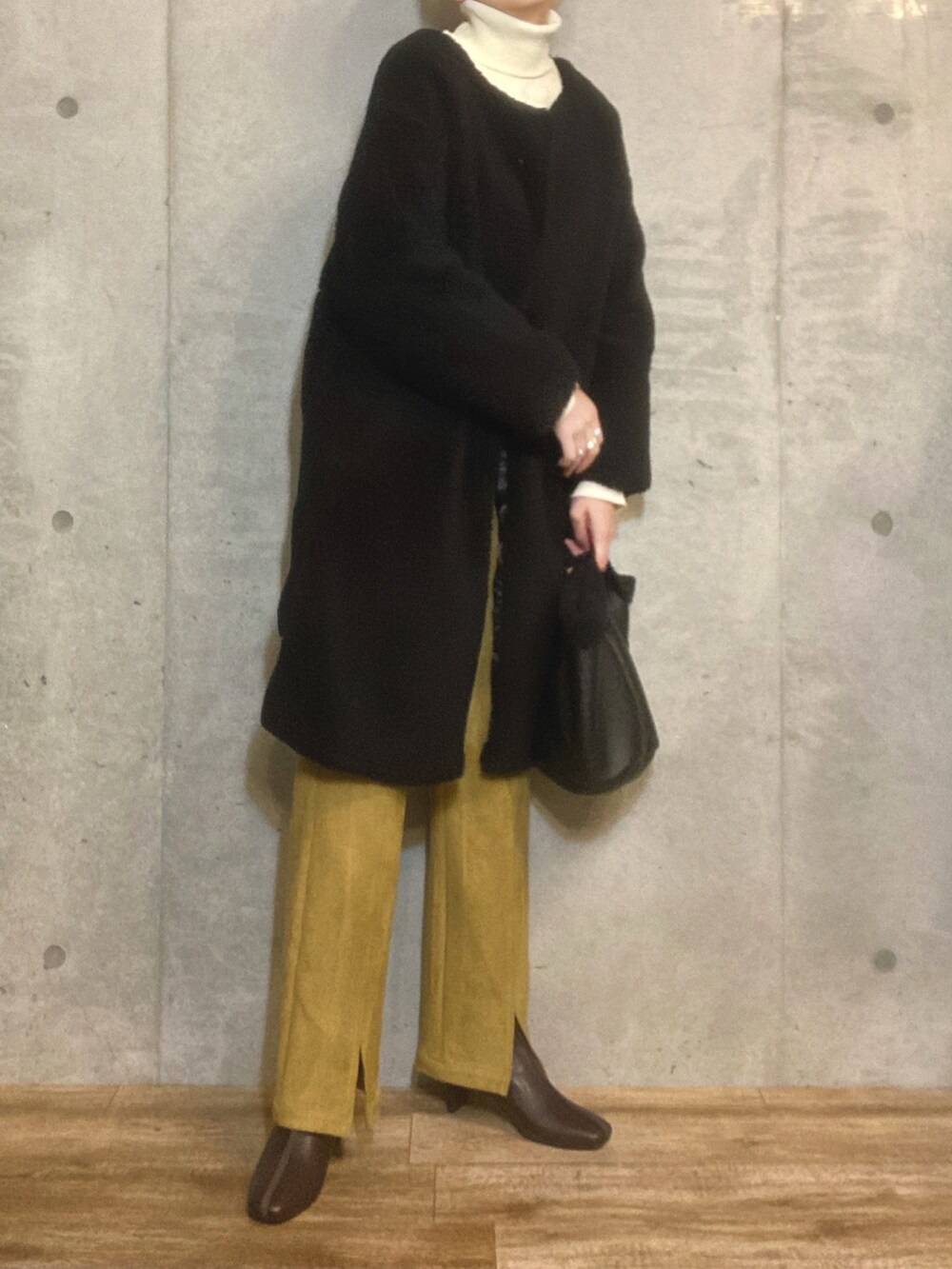 ブラック系のその他アウター、ホワイト系のニット/セーター、ブラック系のトートバッグを着用したレディースの冬コーディネートの2枚目の写真