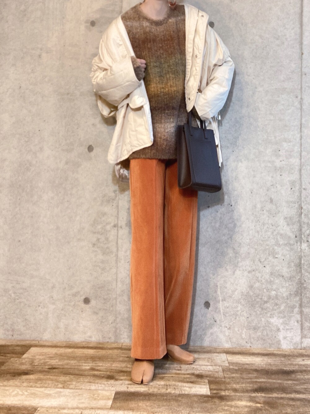 ホワイト系のダウンジャケット/コート、グリーン系のニット/セーター、オレンジ系のその他パンツを着用したレディースの冬コーディネートの2枚目の写真