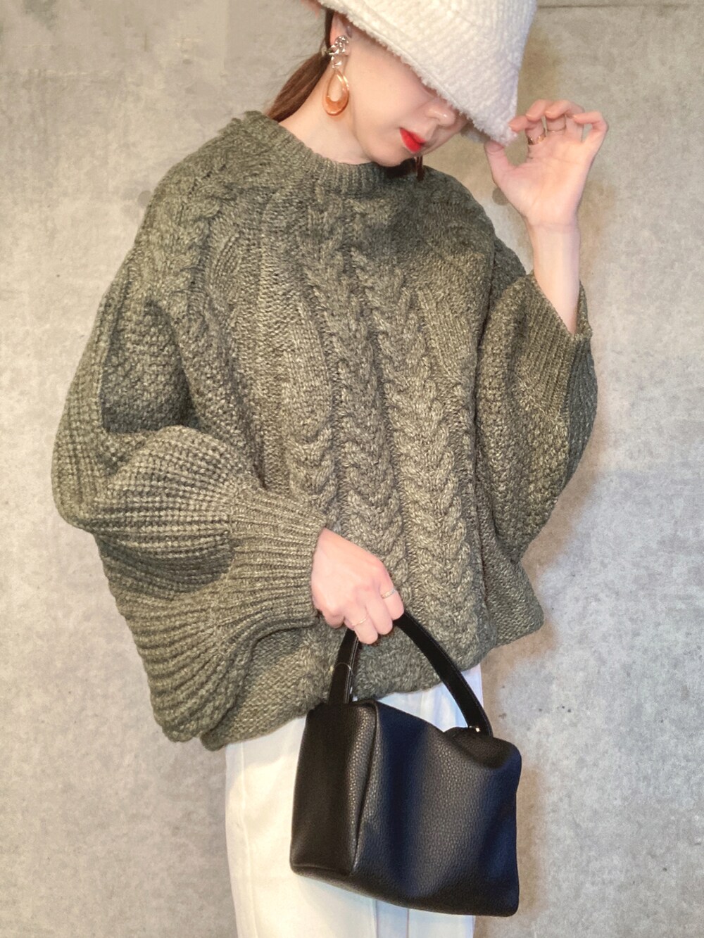 グリーン系のニット/セーター、ブラック系のショルダーバッグ、ホワイト系のスラックスを着用したレディースの冬コーディネートの4枚目の写真