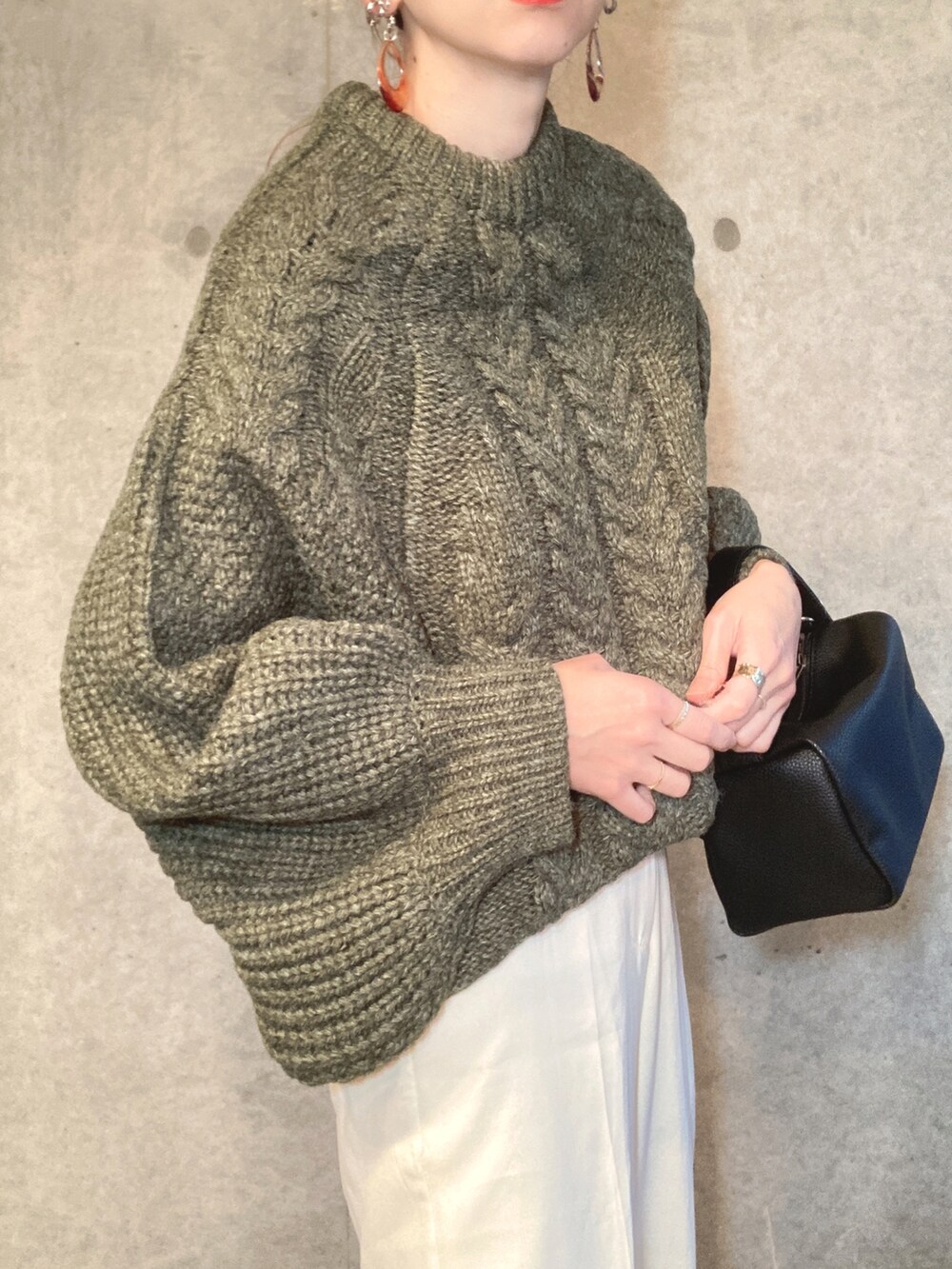 グリーン系のニット/セーター、ブラック系のショルダーバッグ、ホワイト系のスラックスを着用したレディースの冬コーディネートの3枚目の写真