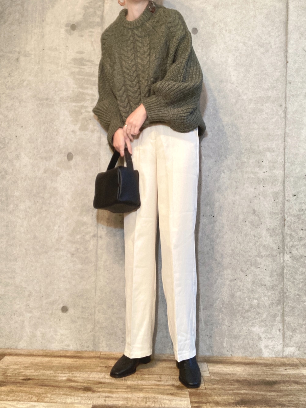 グリーン系のニット/セーター、ブラック系のショルダーバッグ、ホワイト系のスラックスを着用したレディースの冬コーディネートの2枚目の写真