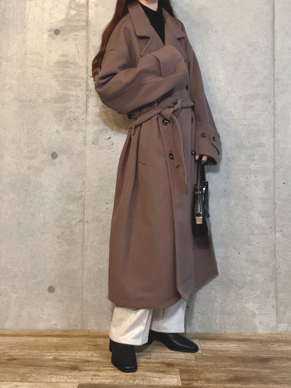 ブラック系のハンドバッグ、ホワイト系のスラックス、ブラウン系のブーツを着用したレディースの冬コーディネートの2枚目の写真