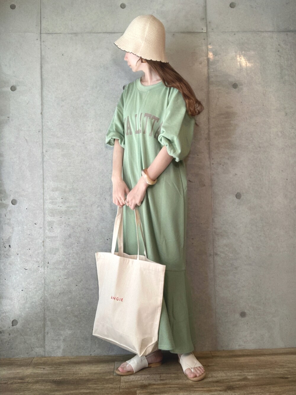 グリーン系のワンピース、ホワイト系のトートバッグ、ホワイト系のサンダルを着用したレディースの春コーディネートの3枚目の写真
