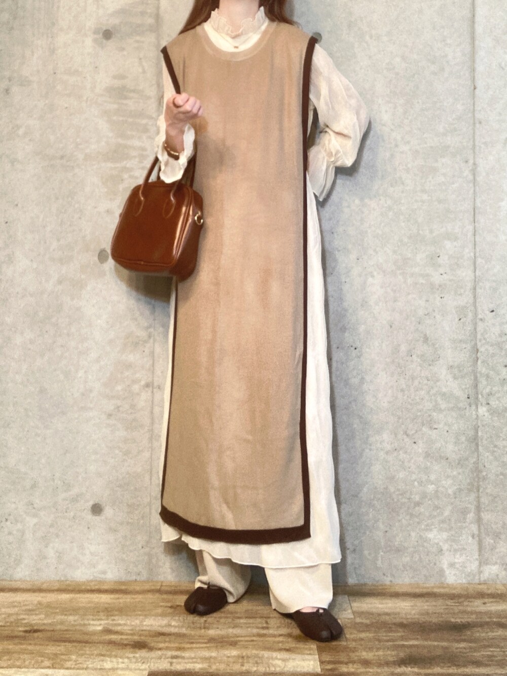 ブラウン系のベスト、ホワイト系のワンピース、ブラウン系のハンドバッグを着用したレディースの秋コーディネートの3枚目の写真