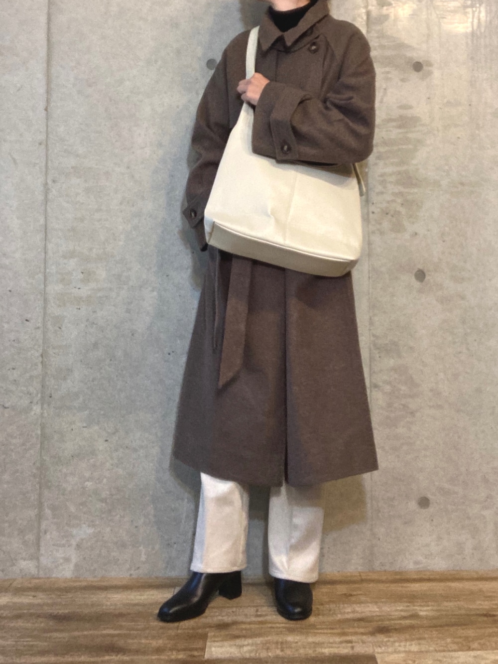 ブラウン系のチェスターコート、ブラック系のTシャツ/カットソー、ホワイト系のボストンバッグを着用したレディースの秋コーディネートの3枚目の写真