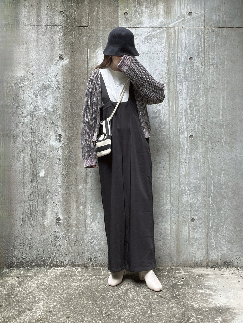 グレー系のニット/セーター、ホワイト系のTシャツ/カットソー、ホワイト系のショルダーバッグを着用したレディースの秋コーディネートの2枚目の写真