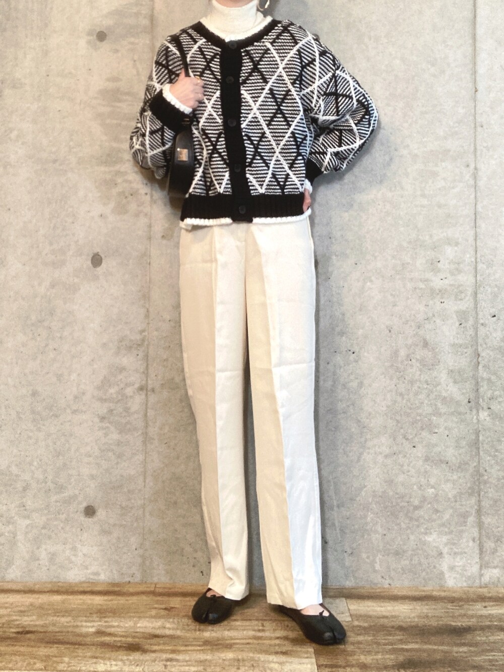 ブラック系のカーディガン/ボレロ、ホワイト系のニット/セーター、ブラック系のハンドバッグを着用したレディースの秋コーディネートの3枚目の写真