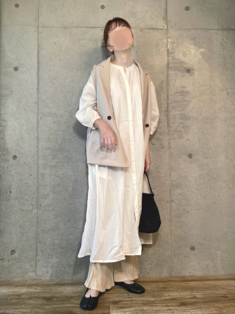 ホワイト系のベスト、ホワイト系のシャツワンピース、ブラック系のショルダーバッグを着用したレディースの夏コーディネートの2枚目の写真