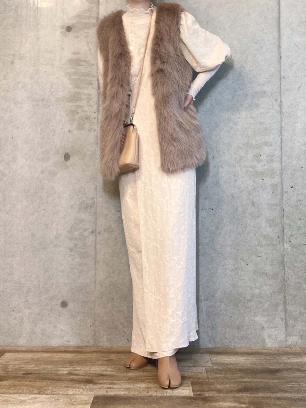 ブラウン系のベスト、ベージュ系のショルダーバッグ、ベージュ系のブーツを着用したレディースの秋コーディネートの2枚目の写真