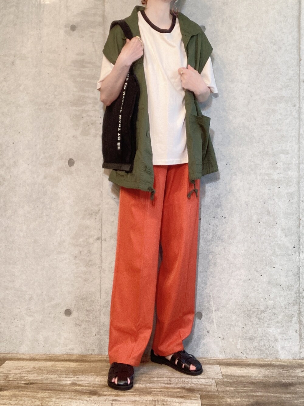 グリーン系のベスト、ベージュ系のTシャツ/カットソー、オレンジ系のスラックスを着用したレディースの夏コーディネートの3枚目の写真