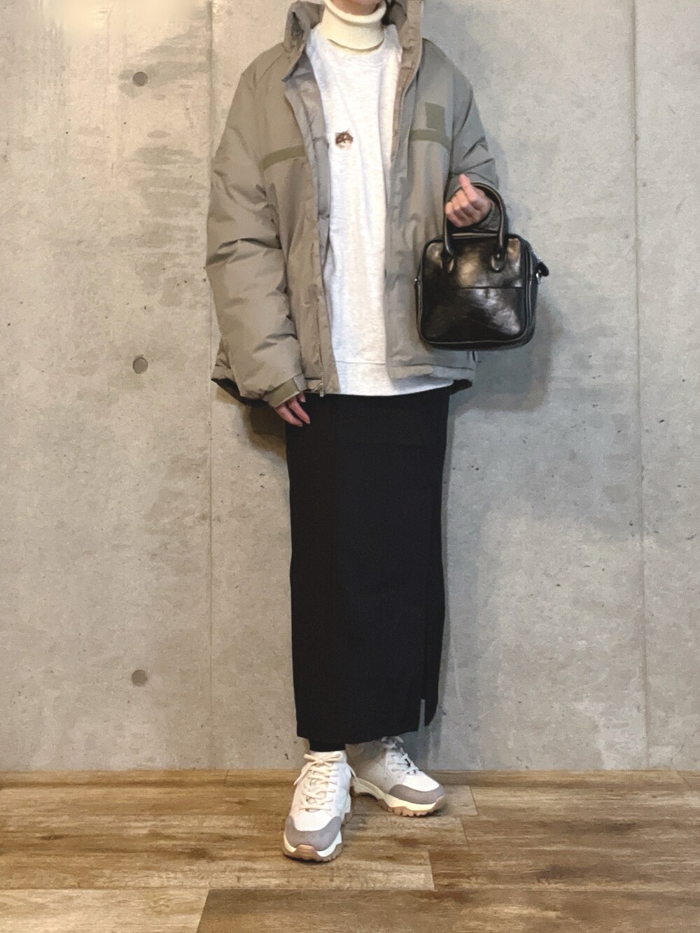 グリーン系のダウンジャケット/コート、ベージュ系のスウェット、ブラック系のショルダーバッグを着用したレディースの冬コーディネートの2枚目の写真