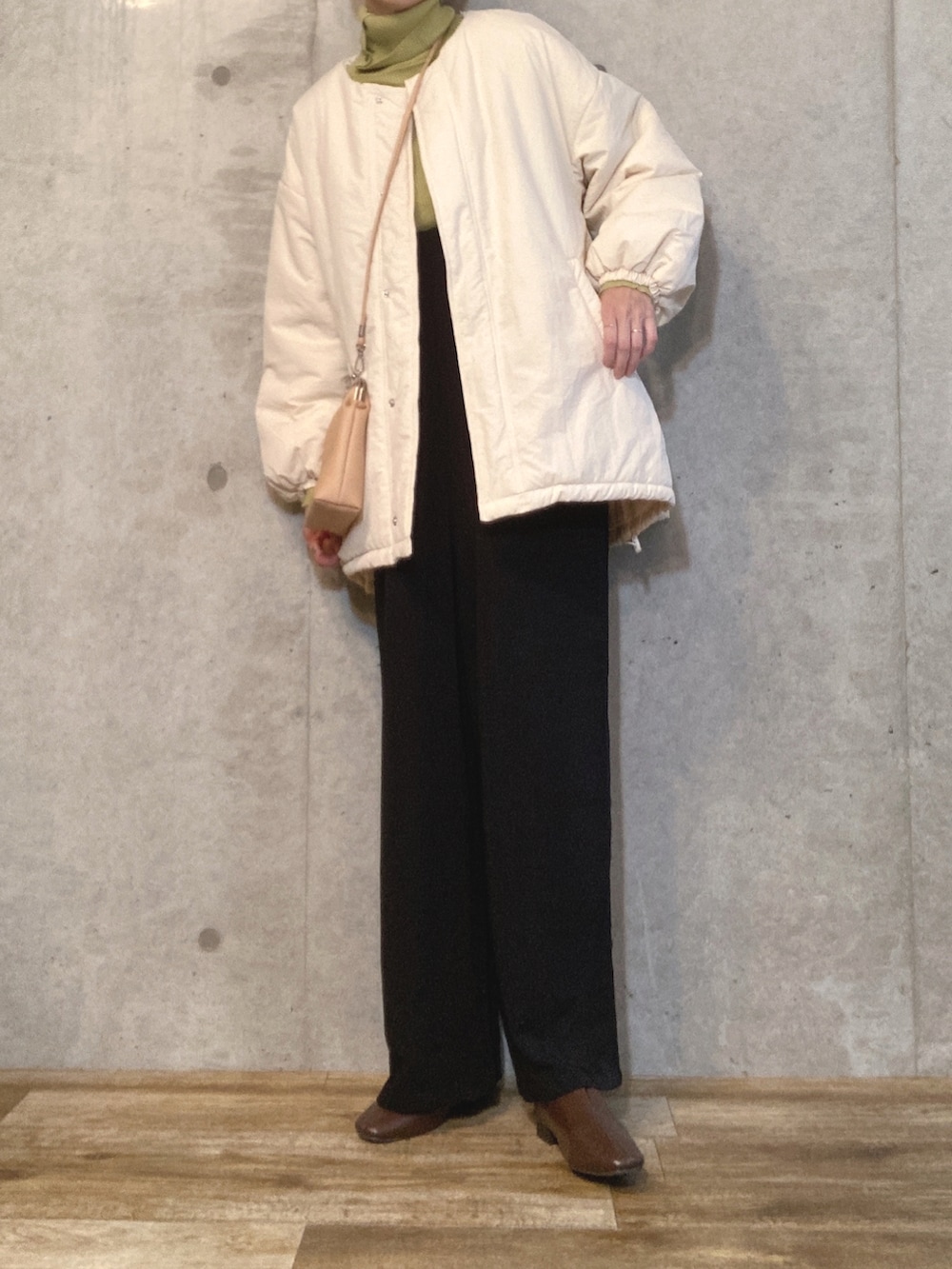 ホワイト系のブルゾン、グリーン系のニット/セーター、ブラック系のサロペット/オーバーオールを着用したレディースの秋コーディネートの3枚目の写真