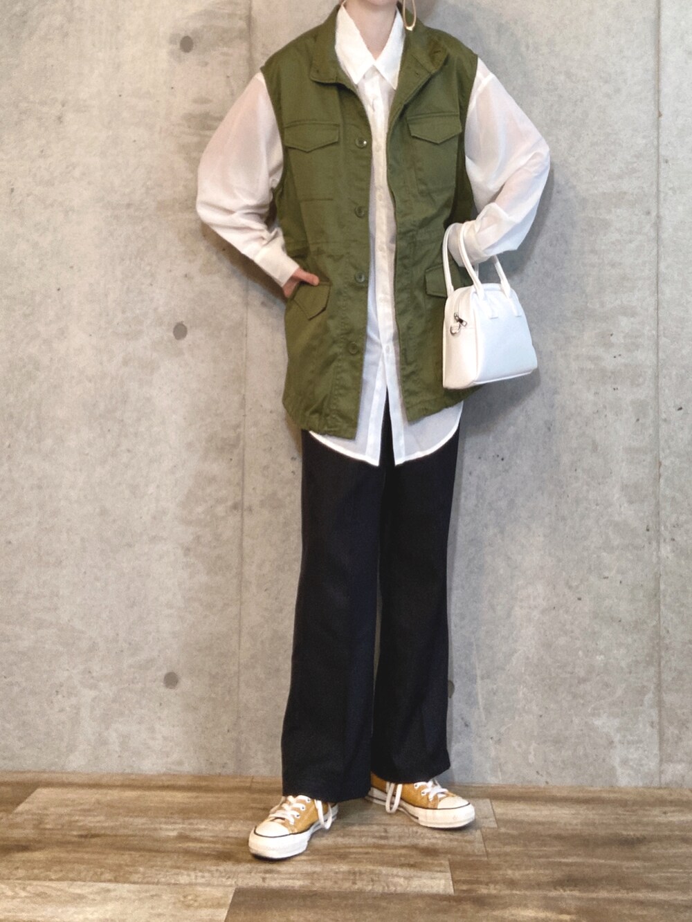 ホワイト系のシャツ/ブラウス、グリーン系のベスト、ブラウン系のトートバッグを着用したレディースの春コーディネートの3枚目の写真