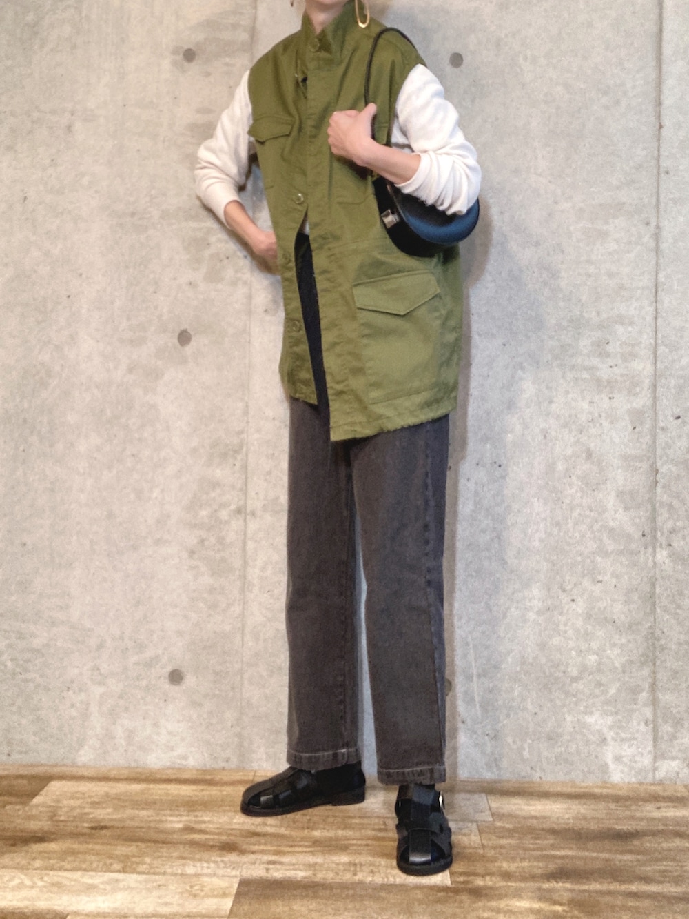 グリーン系のベスト、ブラック系のハンドバッグ、ブラック系のデニムパンツを着用したレディースの春コーディネートの3枚目の写真