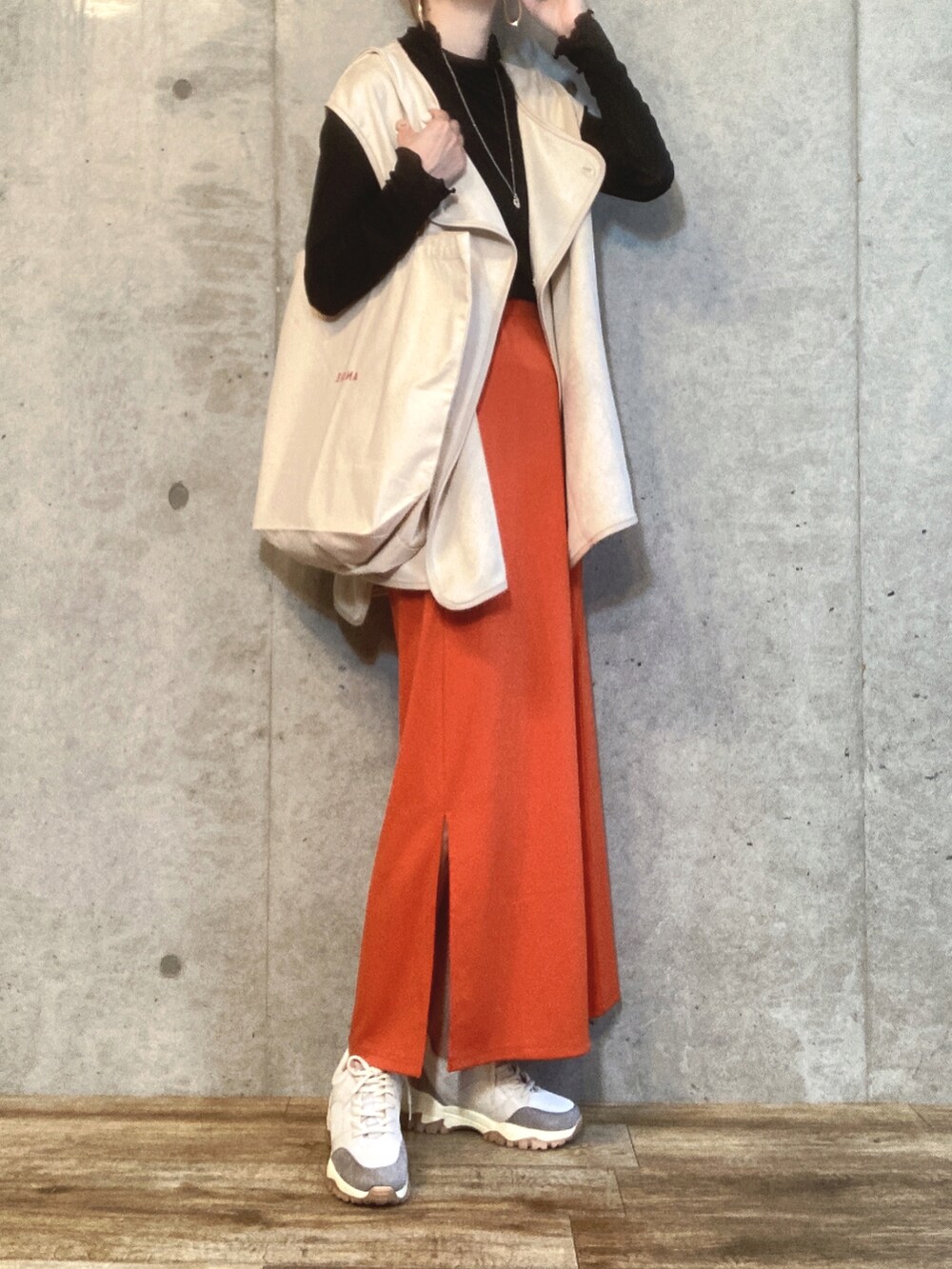 ホワイト系のベスト、ブラック系のTシャツ/カットソー、オレンジ系のスカートを着用したレディースの秋コーディネートの2枚目の写真