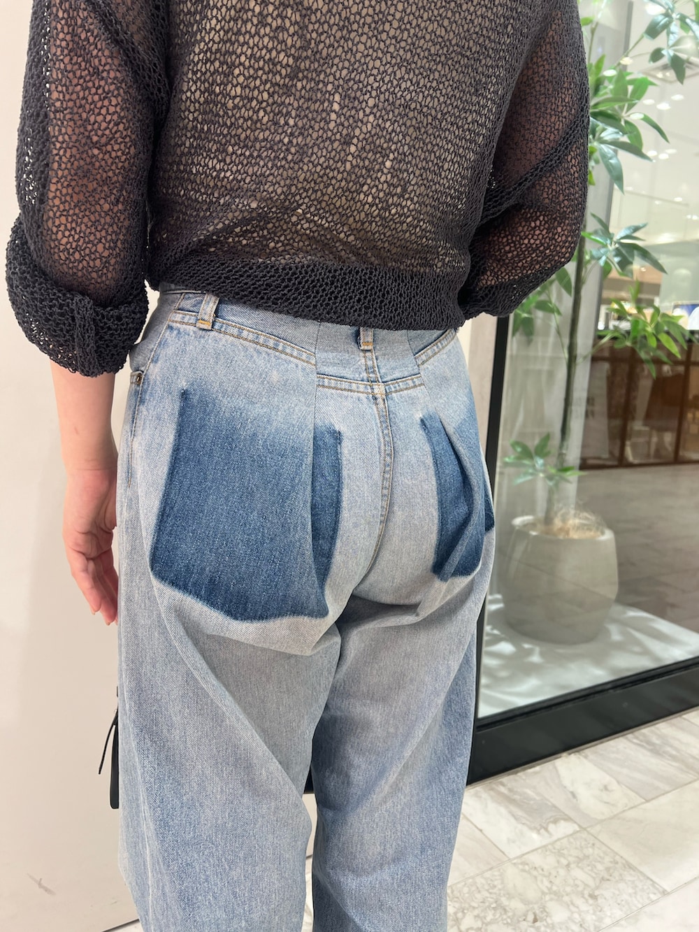 グレー系のニット/セーター、ブルー系のデニムパンツ、ブラック系のハンドバッグを着用したレディースの秋コーディネートの6枚目の写真