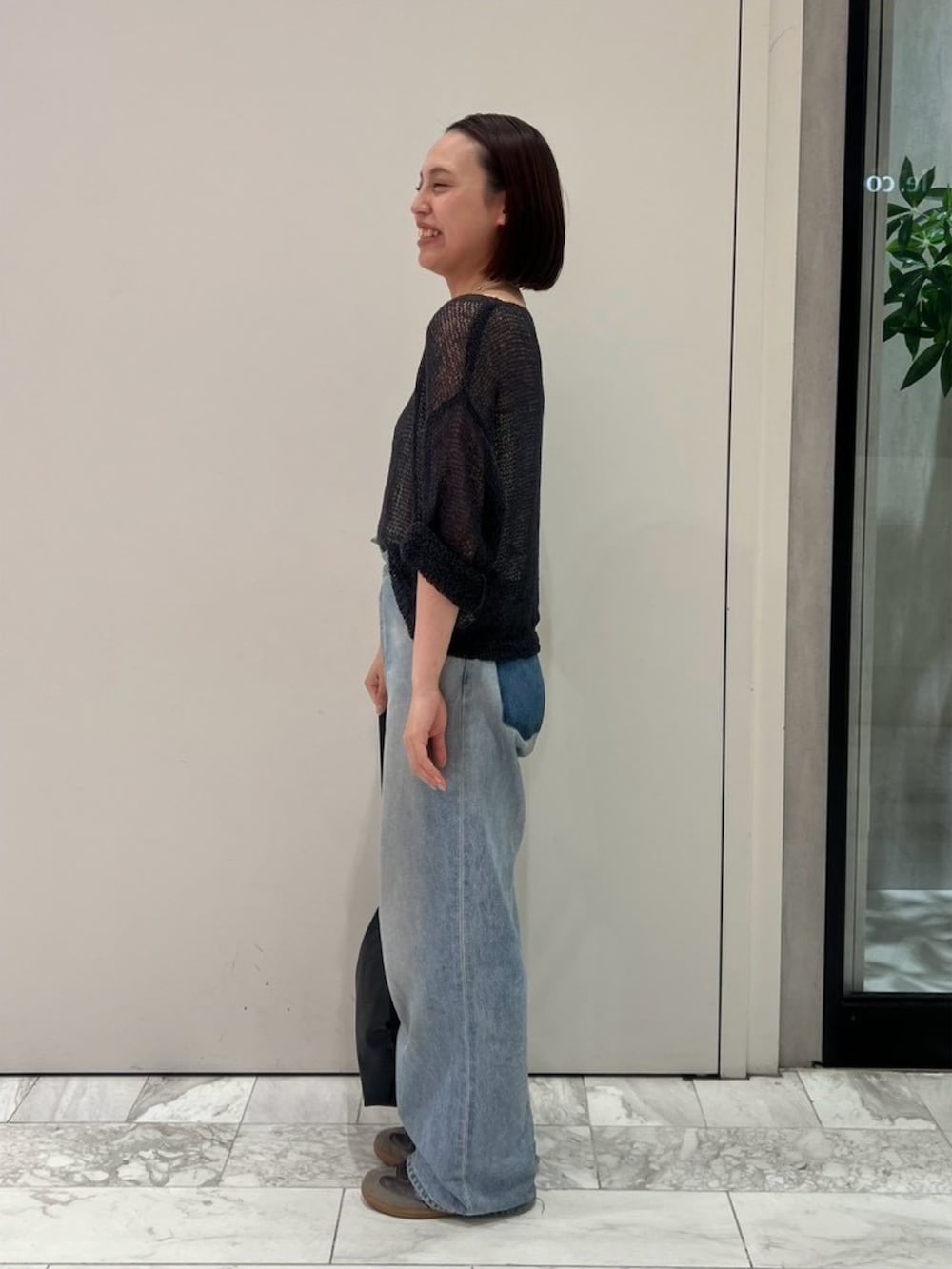 グレー系のニット/セーター、ブルー系のデニムパンツ、ブラック系のハンドバッグを着用したレディースの秋コーディネートの2枚目の写真
