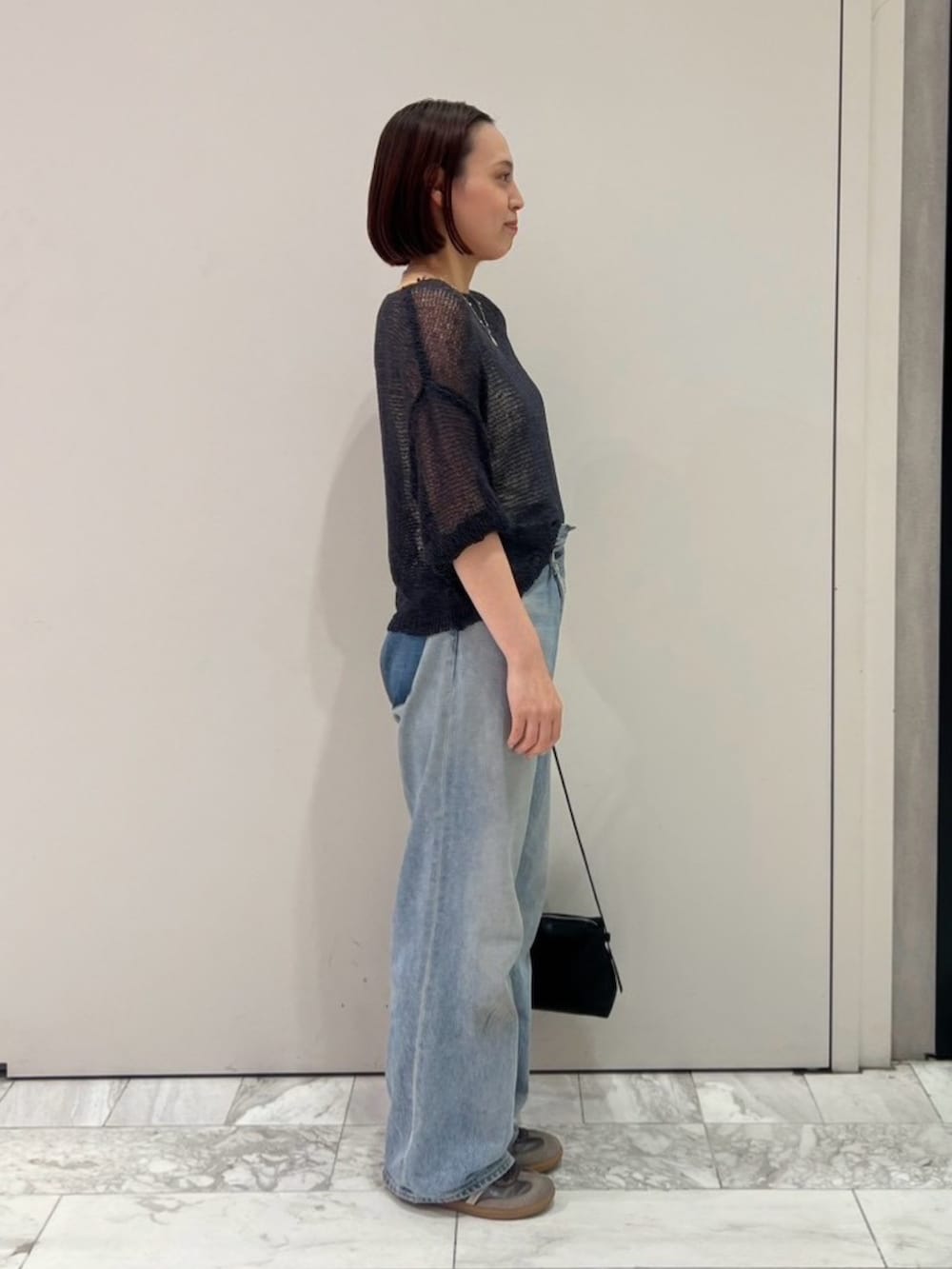グレー系のニット/セーター、ブルー系のデニムパンツ、ブラック系のハンドバッグを着用したレディースの秋コーディネートの4枚目の写真
