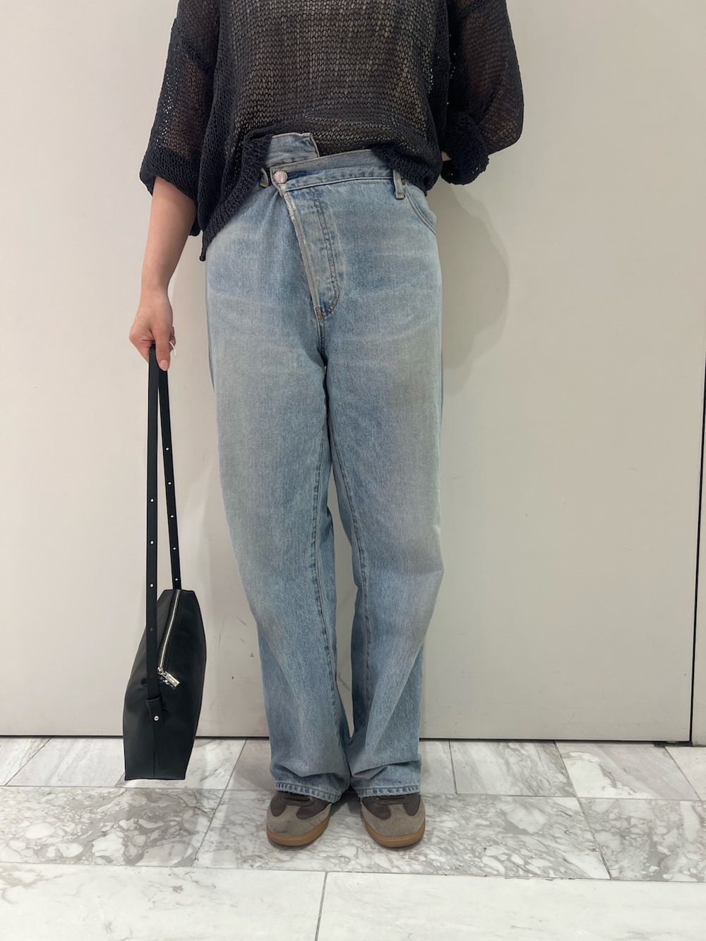 グレー系のニット/セーター、ブルー系のデニムパンツ、ブラック系のハンドバッグを着用したレディースの秋コーディネートの7枚目の写真