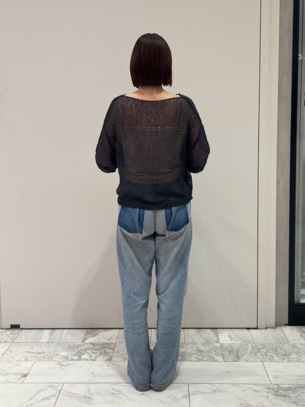 グレー系のニット/セーター、ブルー系のデニムパンツ、ブラック系のハンドバッグを着用したレディースの秋コーディネートの3枚目の写真