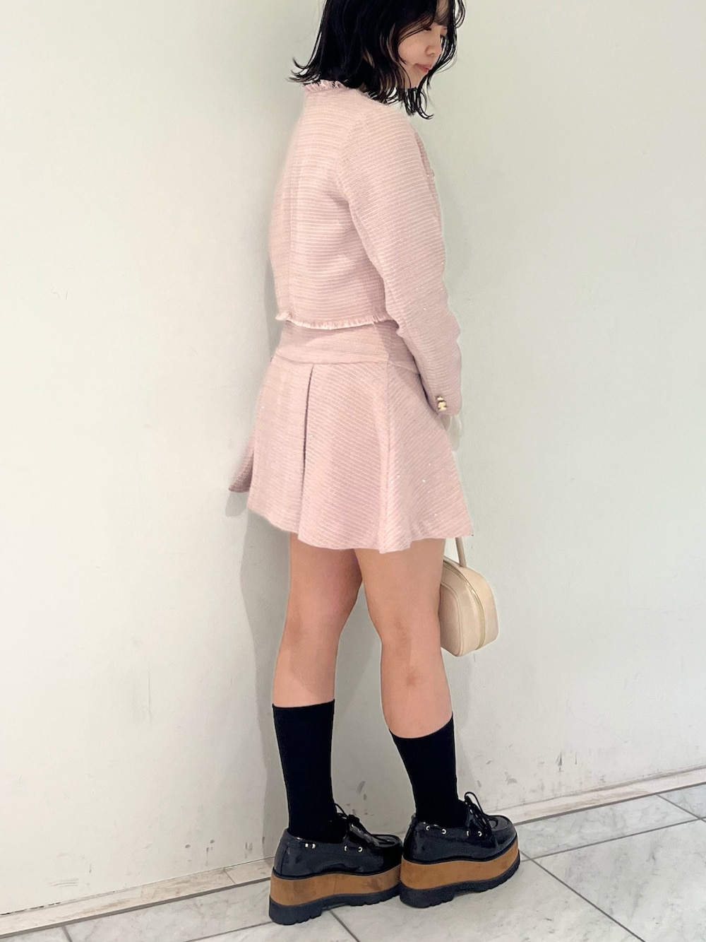 ピンク系のノーカラージャケット、ピンク系のスカート、イエロー系のハンドバッグを着用したレディースの冬コーディネートの3枚目の写真