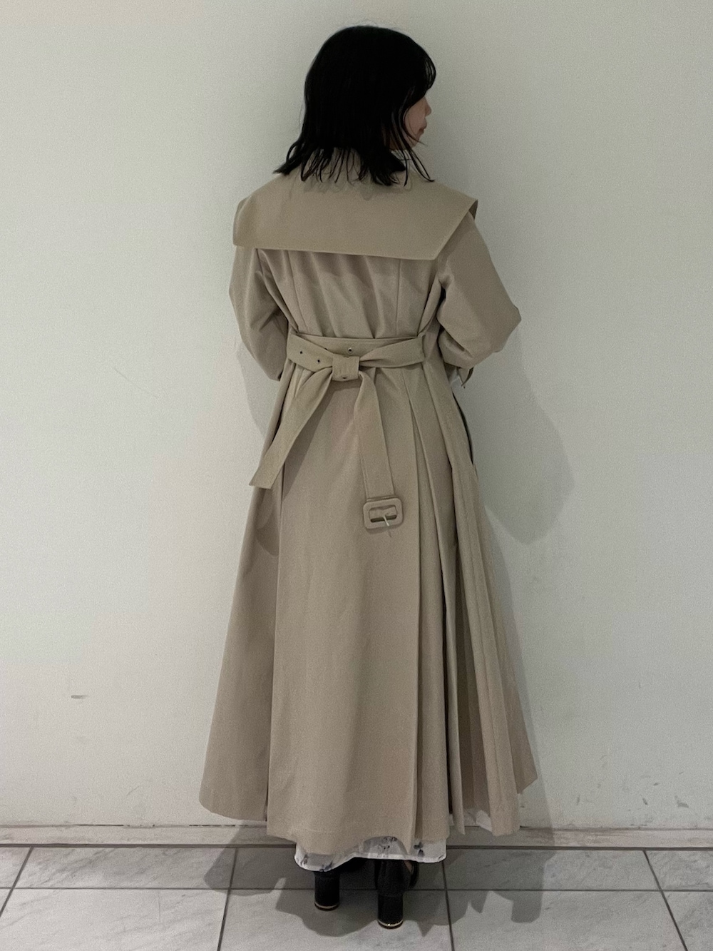 ベージュ系のトレンチコート、ホワイト系のワンピース、ブラック系のサンダルを着用したレディースの春コーディネートの4枚目の写真