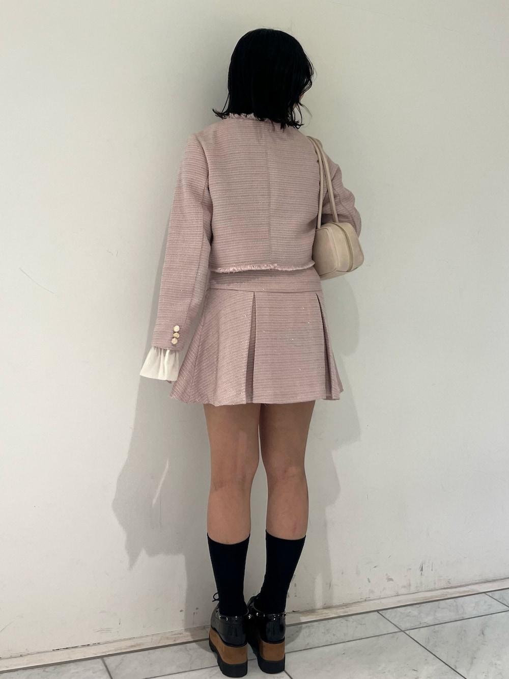 ピンク系のノーカラージャケット、ピンク系のスカート、イエロー系のハンドバッグを着用したレディースの冬コーディネートの4枚目の写真