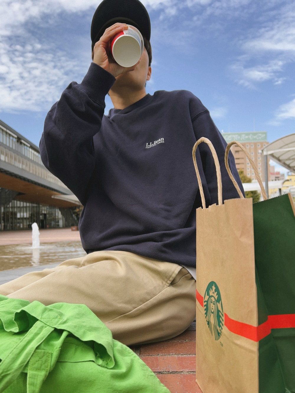 ブルー系のスウェット、ベージュ系のチノパンツ、グリーン系のトートバッグを着用したレディースの秋コーディネートの2枚目の写真