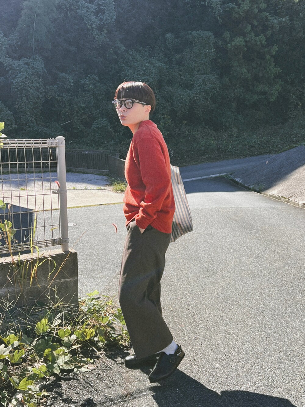 オレンジ系のニット/セーター、ブラウン系のスラックス、ブラック系のシューズを着用したレディースの秋コーディネートの2枚目の写真