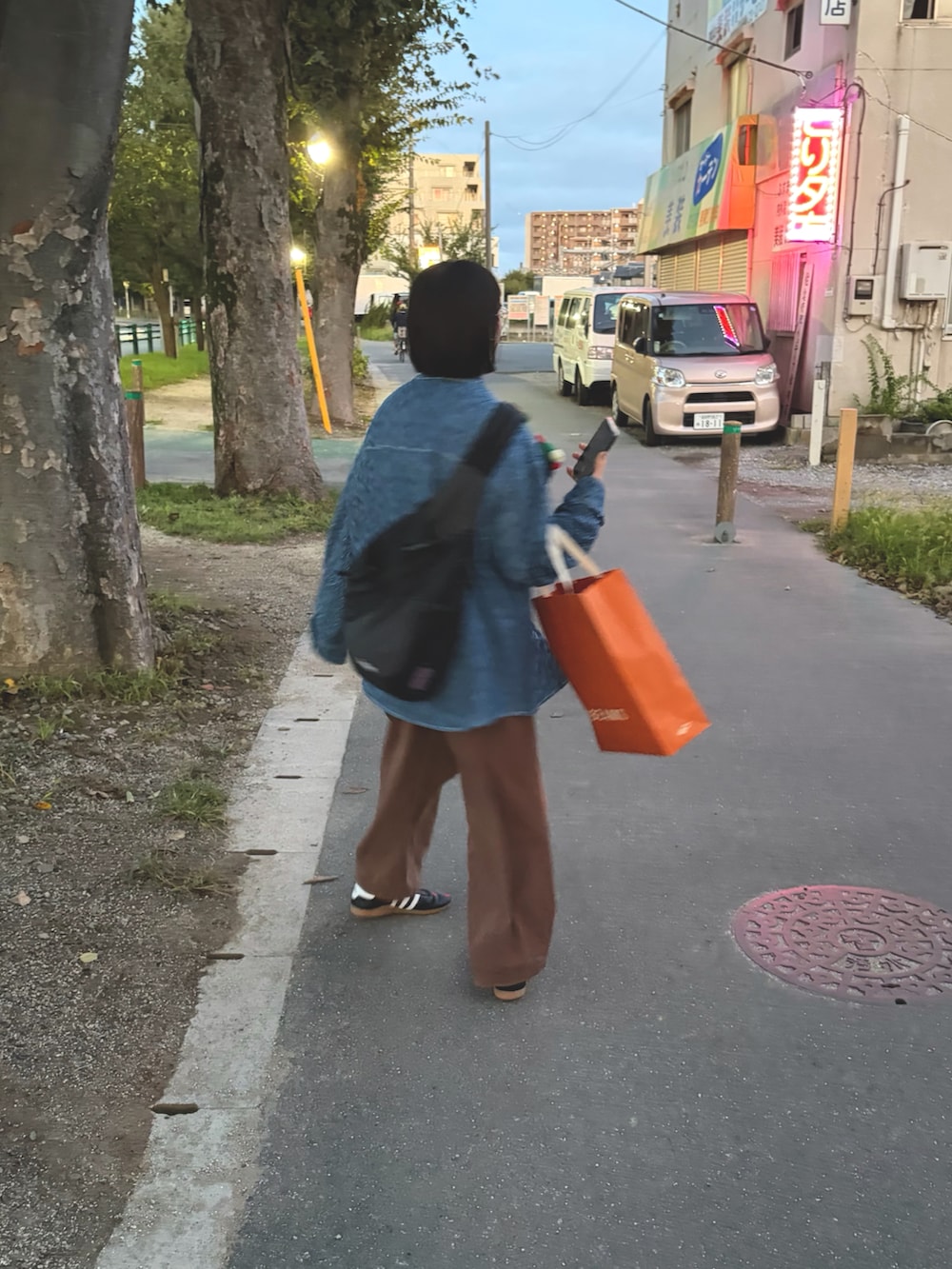 ブラック系のスニーカー、ブラウン系のチノパンツを着用したレディースの秋コーディネートの2枚目の写真