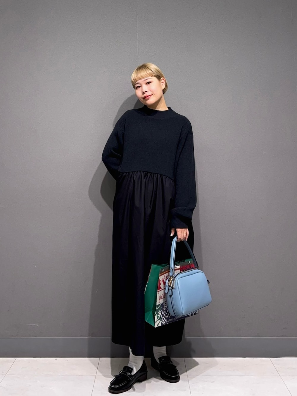 ブラック系のワンピース、ブラック系のローファー、ブルー系のバッグを着用したレディースの秋コーディネートの2枚目の写真