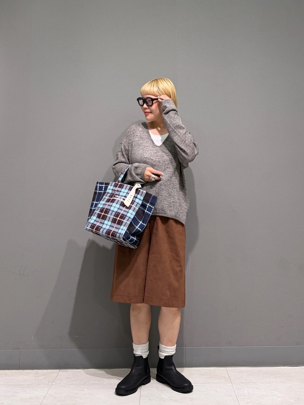グレー系のニット/セーター、ブラウン系のその他パンツ、ブラック系のレインシューズを着用したレディースの秋コーディネートの3枚目の写真
