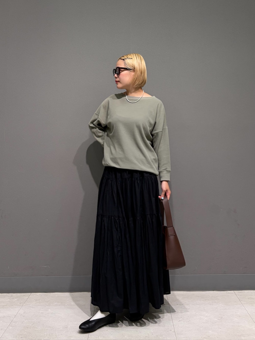 グリーン系のTシャツ/カットソー、ブラック系のスカート、ブラック系のパンプスを着用したレディースの秋コーディネートの5枚目の写真