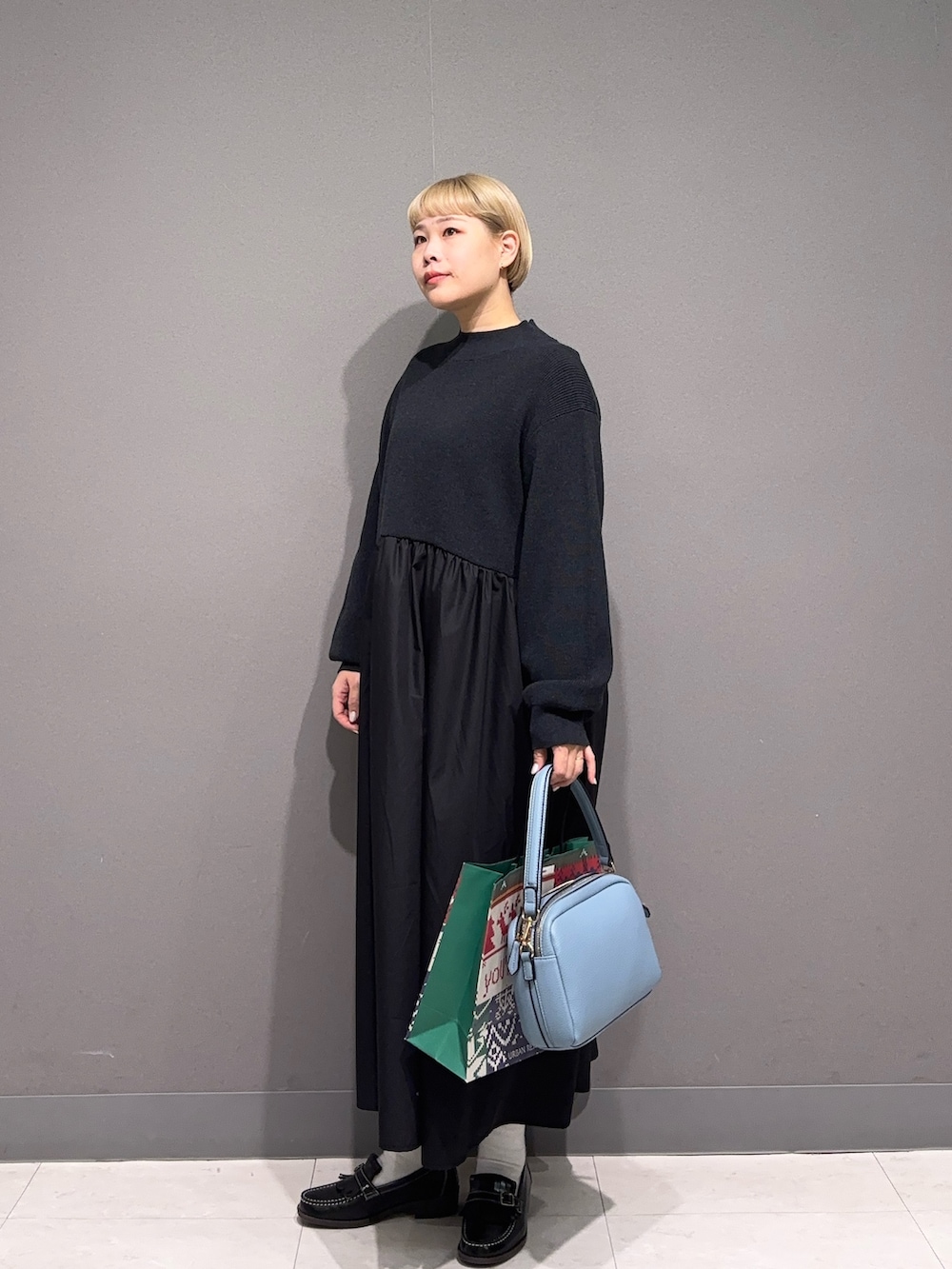 ブラック系のワンピース、ブラック系のローファー、ブルー系のバッグを着用したレディースの秋コーディネートの4枚目の写真