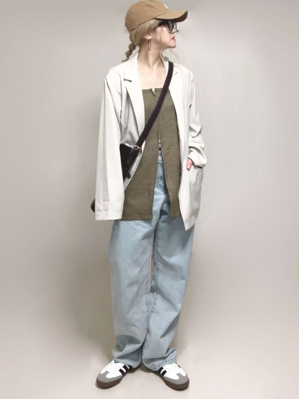 ホワイト系のテーラードジャケット、ブラウン系のベスト、ブルー系のデニムパンツを着用したレディースの春コーディネートの2枚目の写真