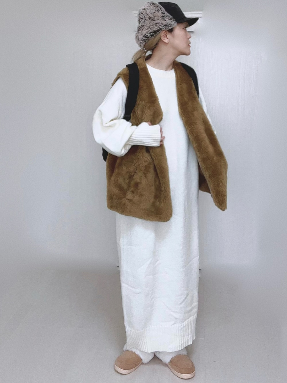 ホワイト系のワンピース、イエロー系のベスト、ブラック系のバックパック/リュックを着用したレディースの冬コーディネートの2枚目の写真