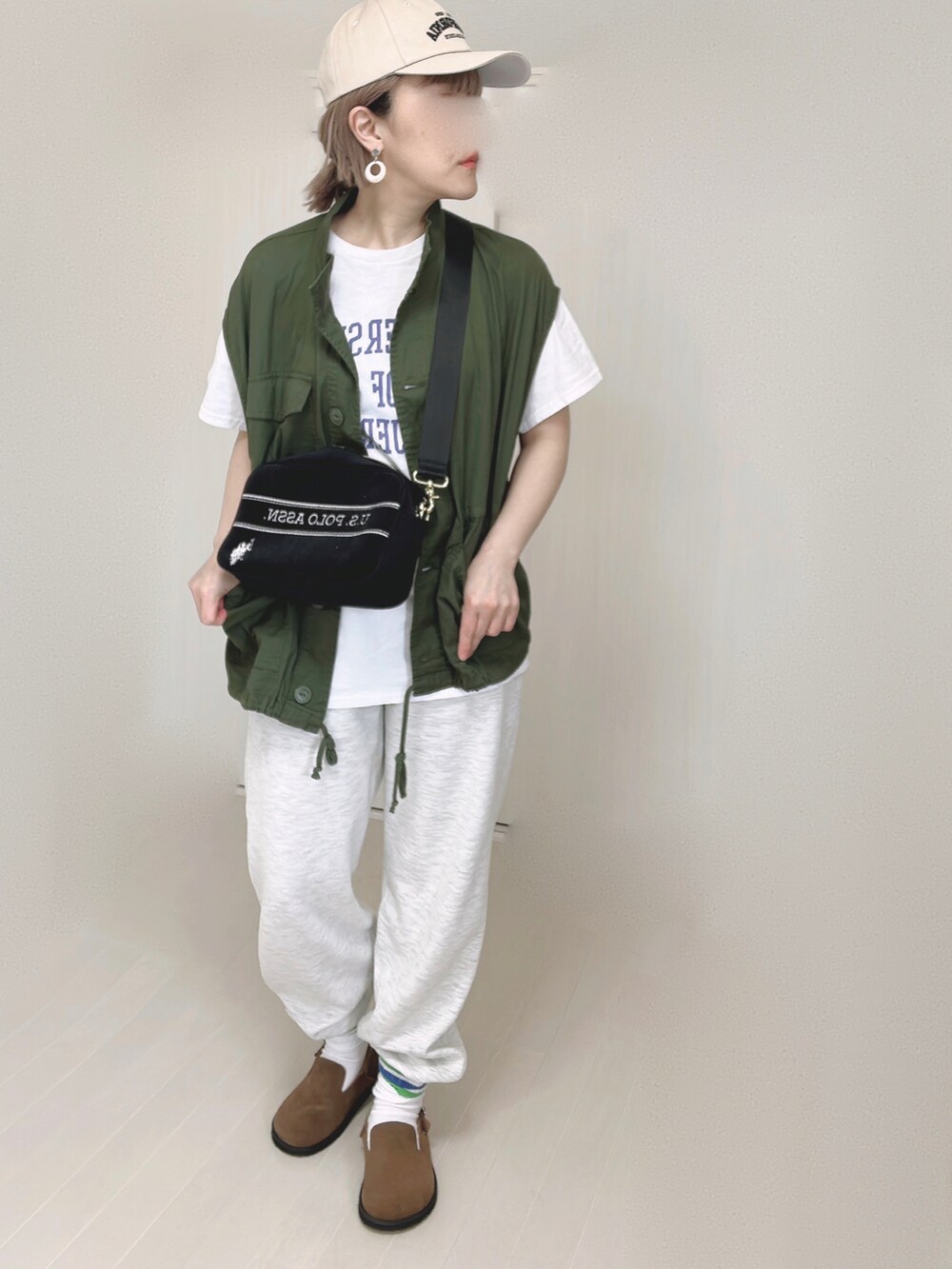 ブラック系のショルダーバッグ、ホワイト系のTシャツ/カットソー、ブラウン系のスリッポンを着用したレディースの春コーディネートの4枚目の写真