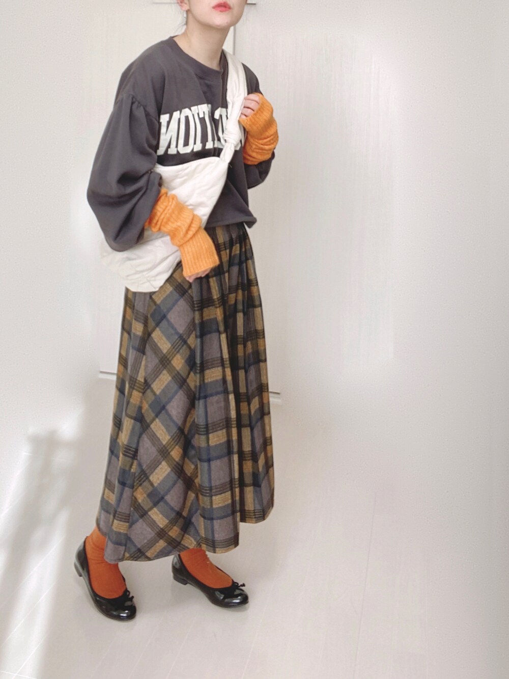 ホワイト系のショルダーバッグ、イエロー系のスカート、ブラック系のバレエシューズを着用したレディースの冬コーディネートの3枚目の写真