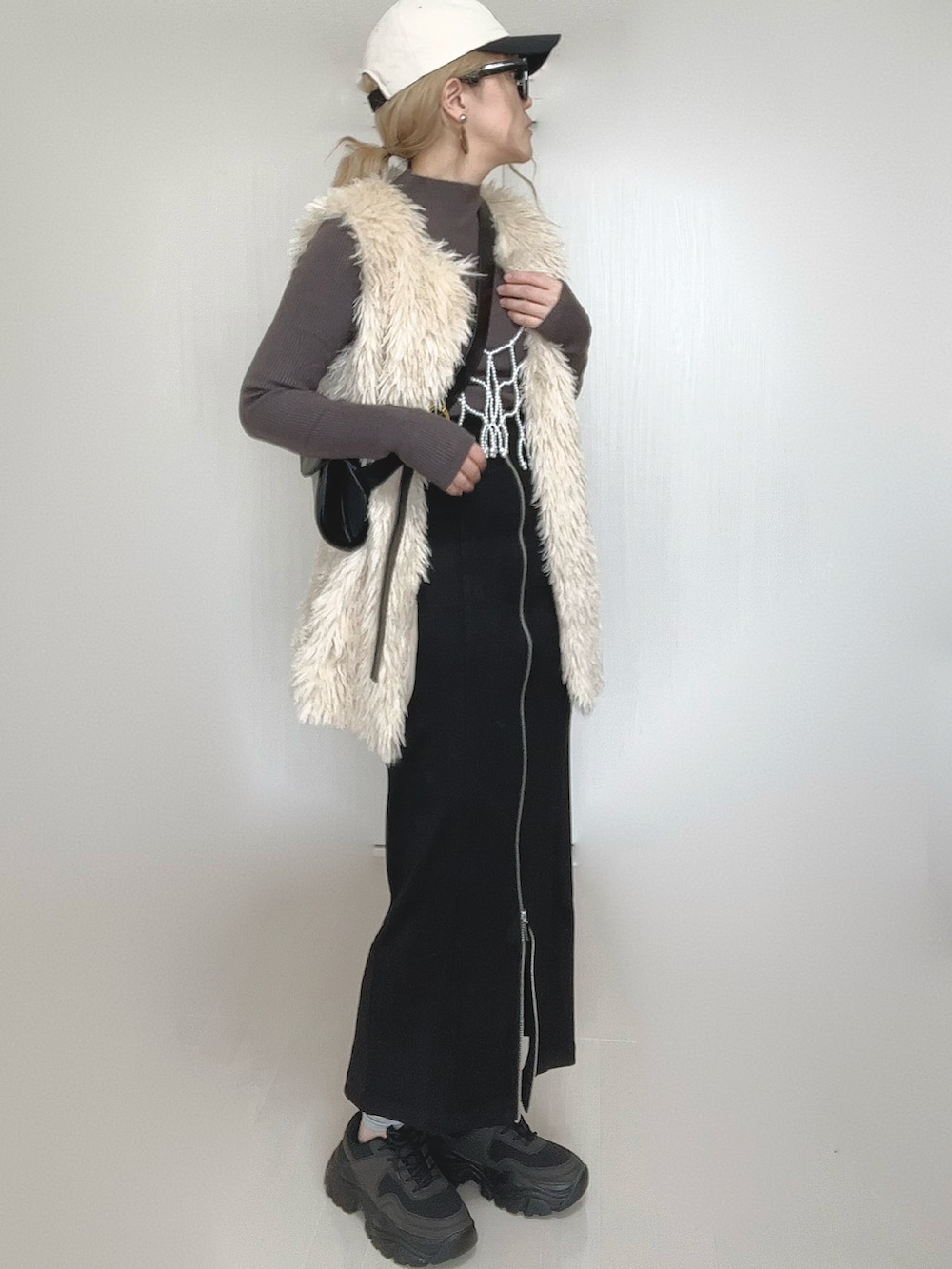 ブラック系のスカート、ホワイト系のベスト、ブラック系のスニーカーを着用したレディースの秋コーディネートの2枚目の写真