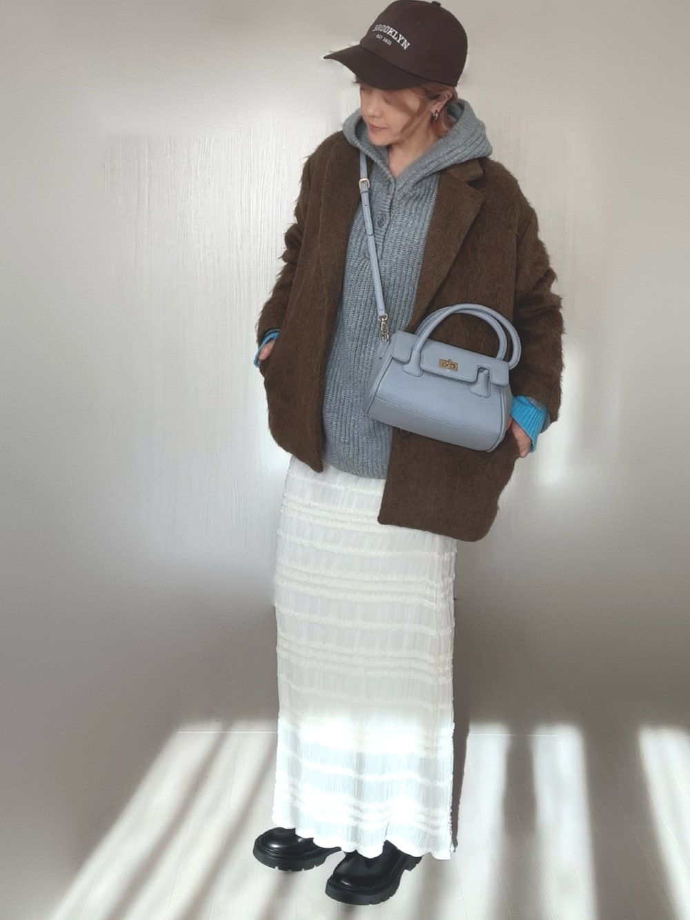 グレー系のニット/セーター、ブラック系のブーツ、ブラウン系のテーラードジャケットを着用したレディースの冬コーディネートの3枚目の写真